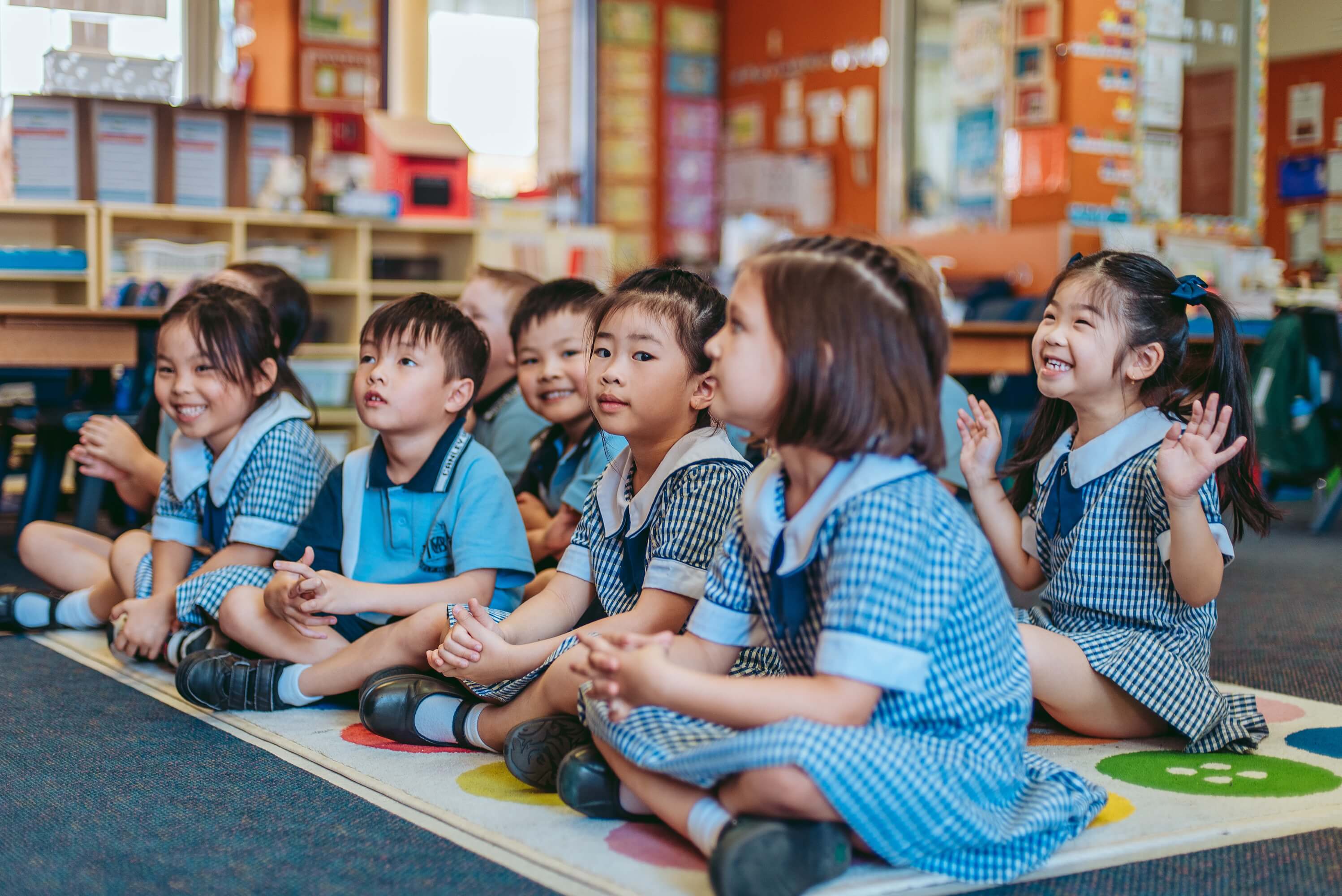 A group of children sitting on the floor in a classroom.