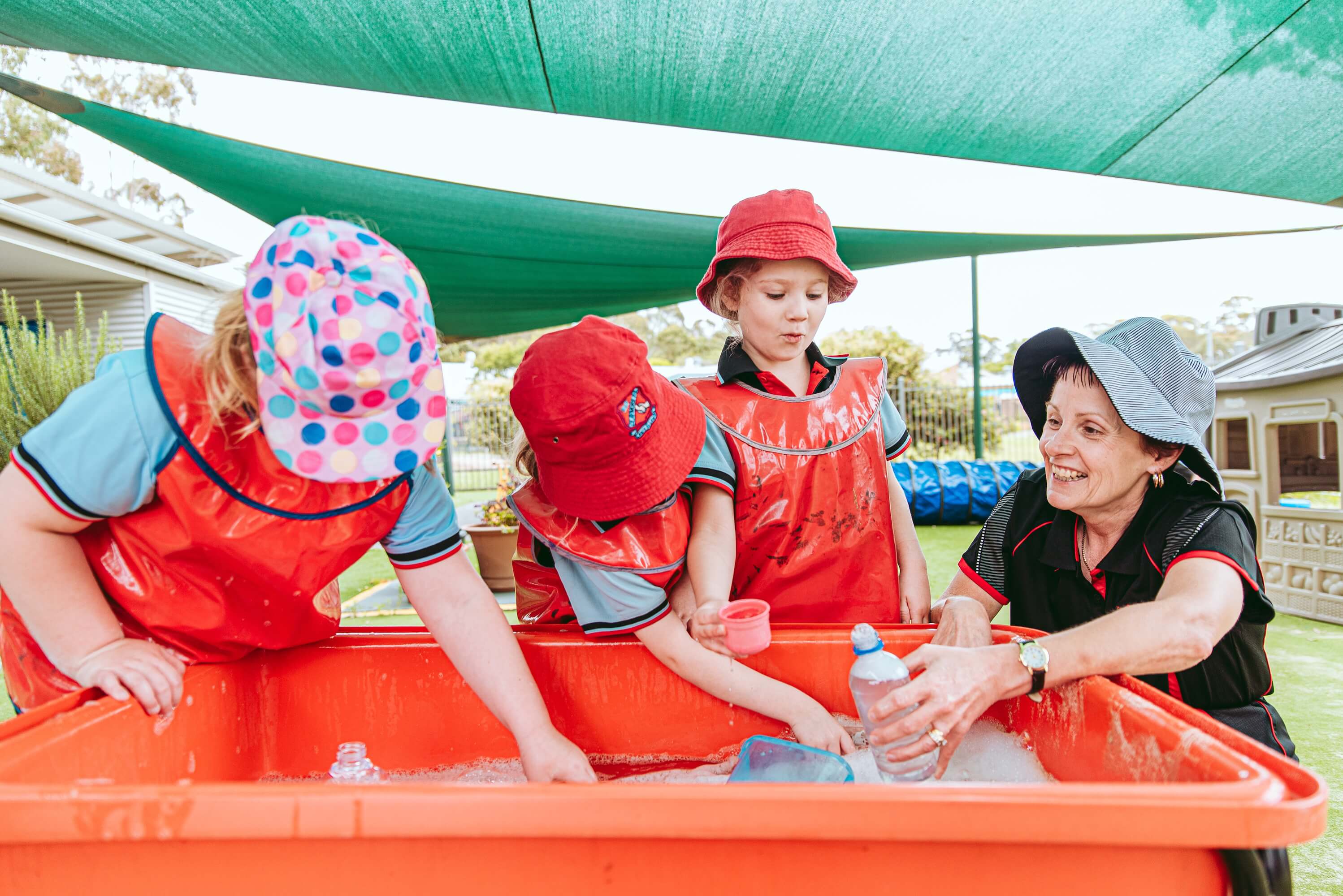 Three children playing in a playground with an educator.