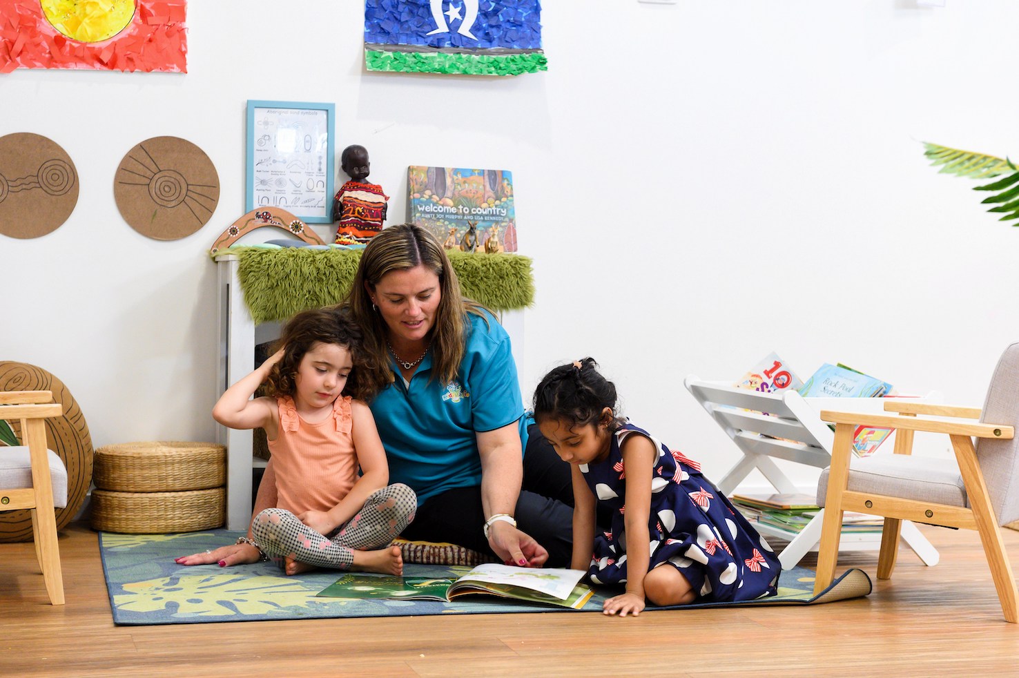 children-reading-with-educator An early childhood educator reading a storybook to two children.